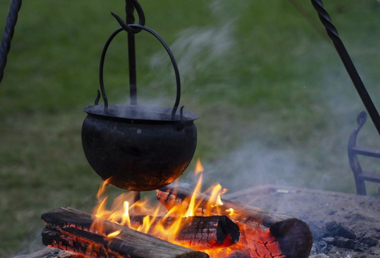 A pot hanging over a wood fire outside