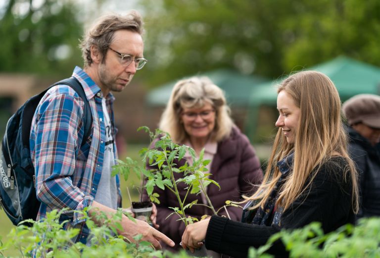 Image shows three people looking at a potted plant
