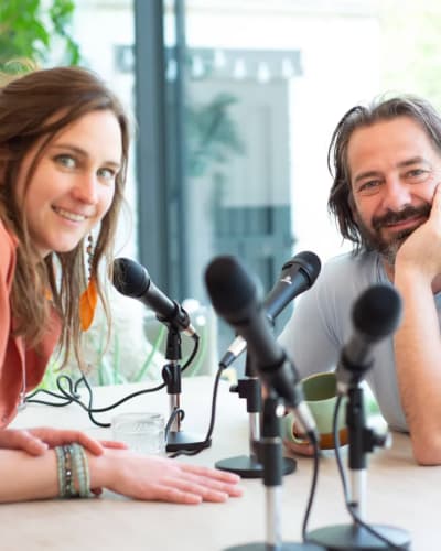 Koen en Griet Alice aan tafel, achter hun podcast microfoons