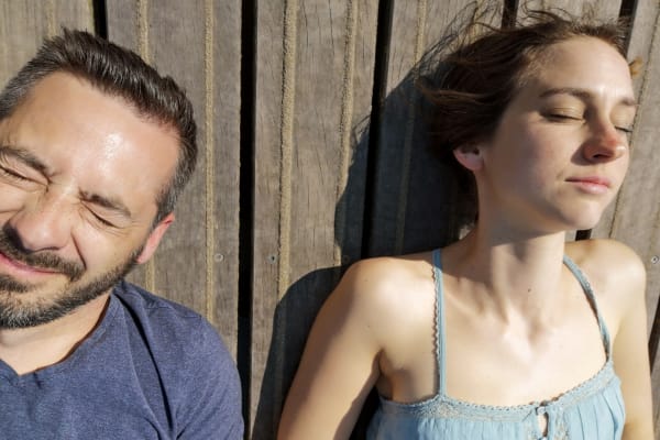 Koen en Griet Alice liggen naast elkaar op hun rug in het gras. Hun ogen dichtgeknepen voor de zon.