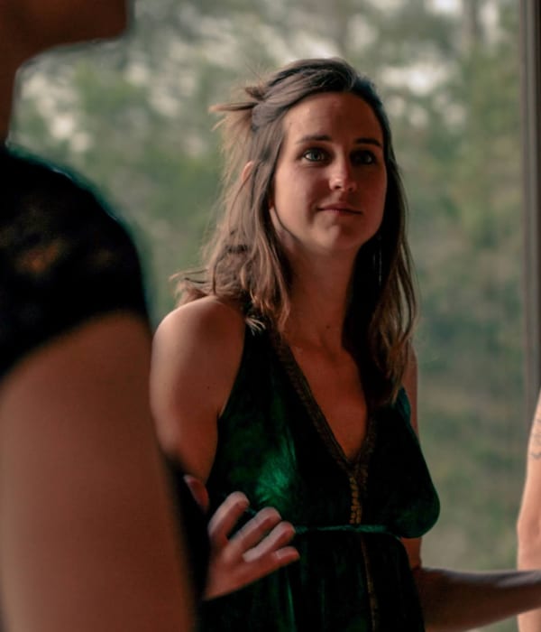 Griet Alice leidt een groep rond vrouwelijk leiderschap, ze draagt een groene jurk en natuur op de achtergrond