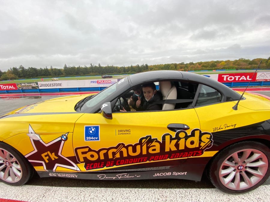 photo d'une bmw de profil avec le moniteur et l'enfant dans la voiture de course