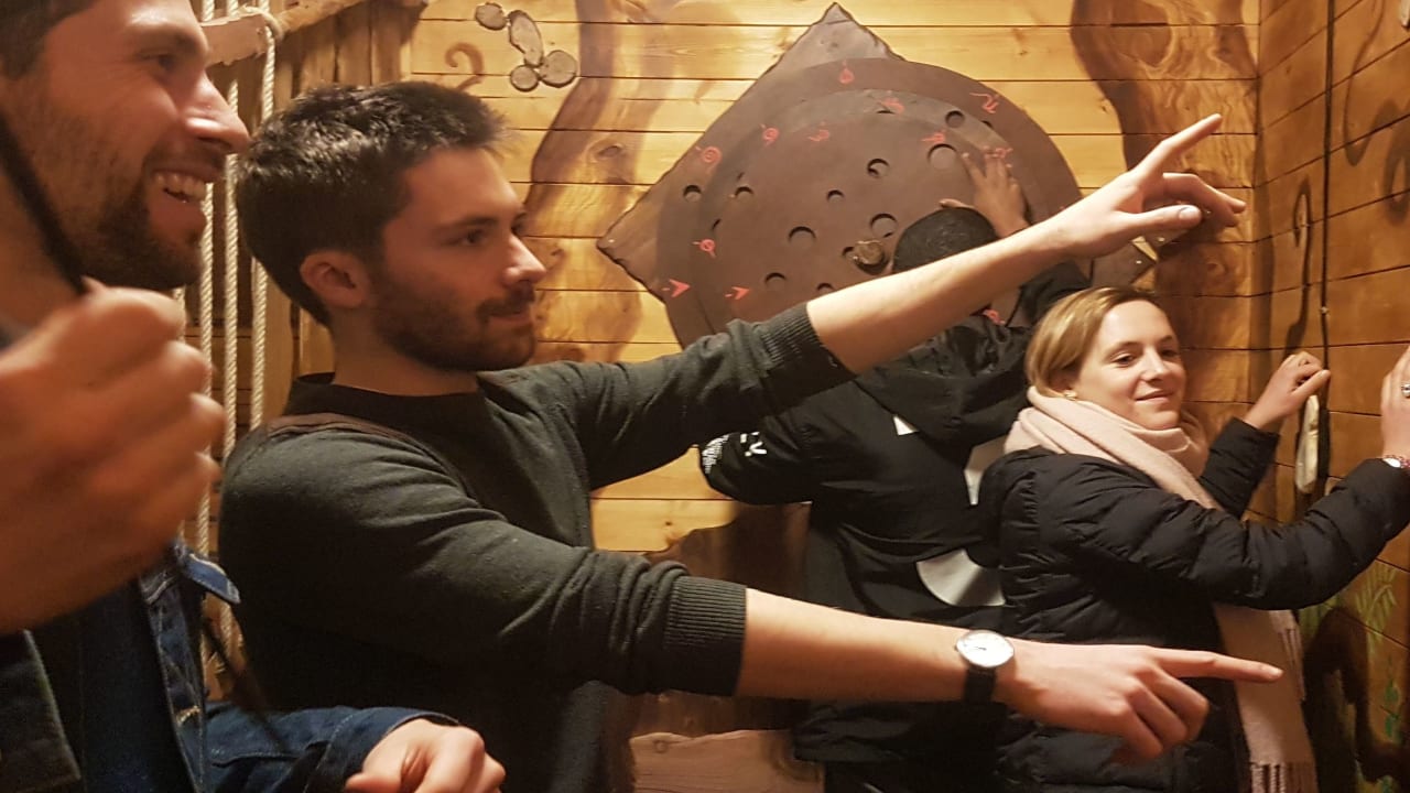 équipe dans une pièce d'escape game avec enigmes sur les murs en bois