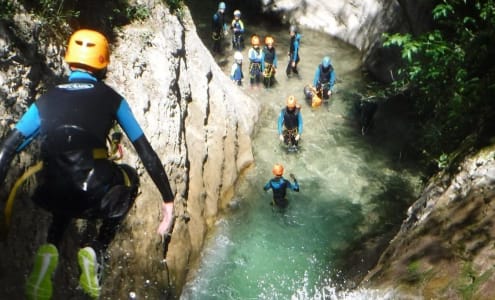 personne qui saut dans l'eau devant un groupe de canyoning