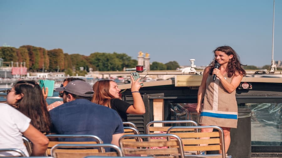 Une femme guide avec le sourire entrain de commanter une croisiere sur le toit d'une péniche à Paris