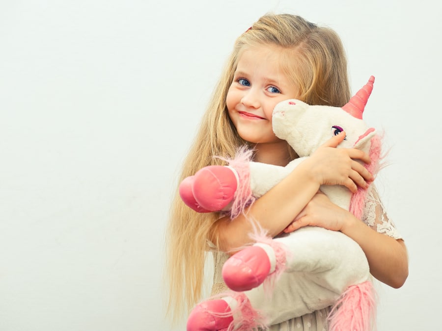 petite fille qui fait un calin à une licorne en peluche