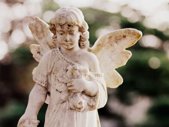 An angel carved out of stone on a grave, symbolizing the cremation services offered by funeral homes on Funeralocity, a comparison website