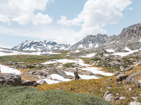 A woman hiking in the Rocky Mountains to scatter the ashes of a loved one after using Funeralocity to find a funeral home to perform the cremation