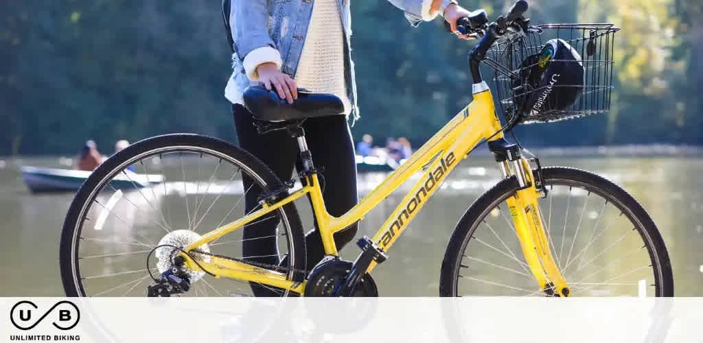 Description: This image features the mid-section of an individual standing alongside a bright yellow Cannondale bicycle. The person, wearing a light-colored denim jacket and dark pants, is holding onto the bike's handle with one hand and the saddle with the other hand, but their head is not visible in the shot. On the handle of the bicycle, there is a black basket containing an item. In the background, a calm body of water is visible, upon which a small boat with at least one occupant can be seen. The setting appears to be a pleasant, sunlit day ideal for outdoor activities. The logo in the lower-left corner reads "U B," suggesting the concept of 'Unlimited Biking' directly above.

To add to the enjoyment of your next outdoor adventure, FunEx.com offers unbeatable savings on tickets for a plethora of experiences with the promise of the lowest prices guaranteed.