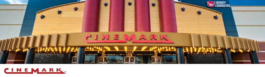 Exterior of a Cinemark theater with a lit marquee and clear blue sky.