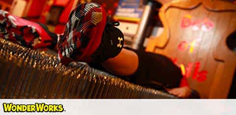 Child in sneakers lying down at a colorful play area marked "WonderWorks."