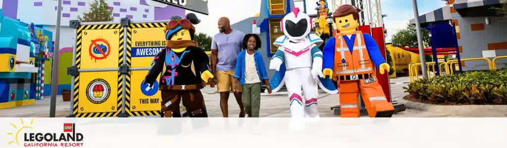 Promotional banner depicting a vibrant LEGOLAND California Resort scene. Two animated LEGO characters, a space figure and a construction worker, stand beside a family of three happily walking together. A colorful backdrop with LEGO structures enhances the playful atmosphere. The resort's logo anchors the image foreground.