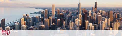 Image showing a panoramic view of a city skyline with skyscrapers bathed in warm sunlight. In the foreground, the Big Bus logo is visible, indicating a sightseeing tour service. The calm waters of a lake line the city, and a clear sky completes the serene cityscape.