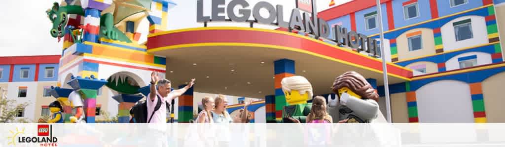 Entrance to LEGOLAND Hotel with colorful LEGO brick designs. Visitors and LEGO figures are visible in front, under the hotel's large sign. The building exudes a playful and welcoming atmosphere for families.