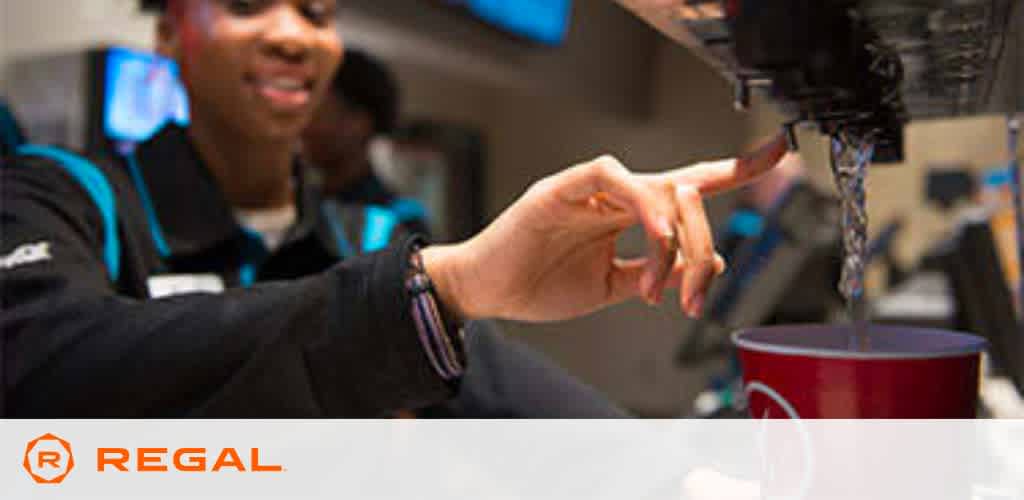 Employee pouring a drink at a Regal cinema concession stand.