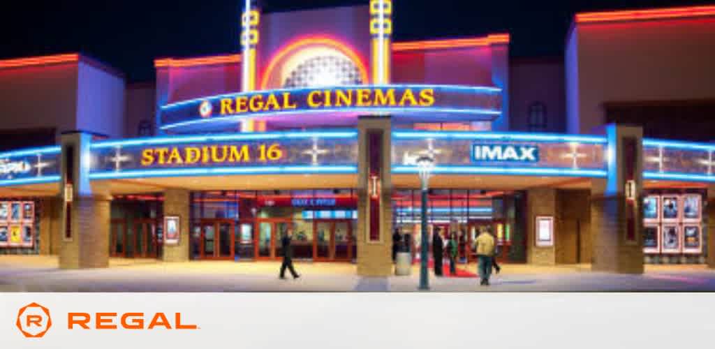 Exterior of a Regal Cinemas movie theater at dusk. The entrance is brightly lit with neon signs saying  REGAL CINEMAS,   STADIUM 16,  and  IMAX.  Patrons are visible entering and leaving, evoking a bustling movie-going experience. The cinema's branding is prominent on the top left.