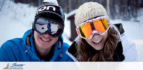 This image depicts two joyful individuals enjoying a winter setting, likely at a ski resort. The person on the left is wearing a blue jacket and a black beanie with the logo "ION" across the front, paired with goggles featuring a reflection of the snowy scene. The person on the right is sporting a white beanie, goggles with orange tint, and a smile that conveys the excitement of a day spent in the snow. Both individuals appear to be bundled up for chilly weather and are surrounded by a snowy environment, indicated by the white, frosty blur in the background and falling snowflakes. The bottom left corner features the logo for "Snow Valley."

Discover the thrill of snowy adventures and save on your next getaway with FunEx.com, where we always strive to offer the lowest prices and greatest savings on tickets for your favorite destinations!