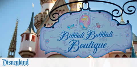 Sign for "Bibbidi Bobbidi Boutique" at a theme park with a pink castle in the background.