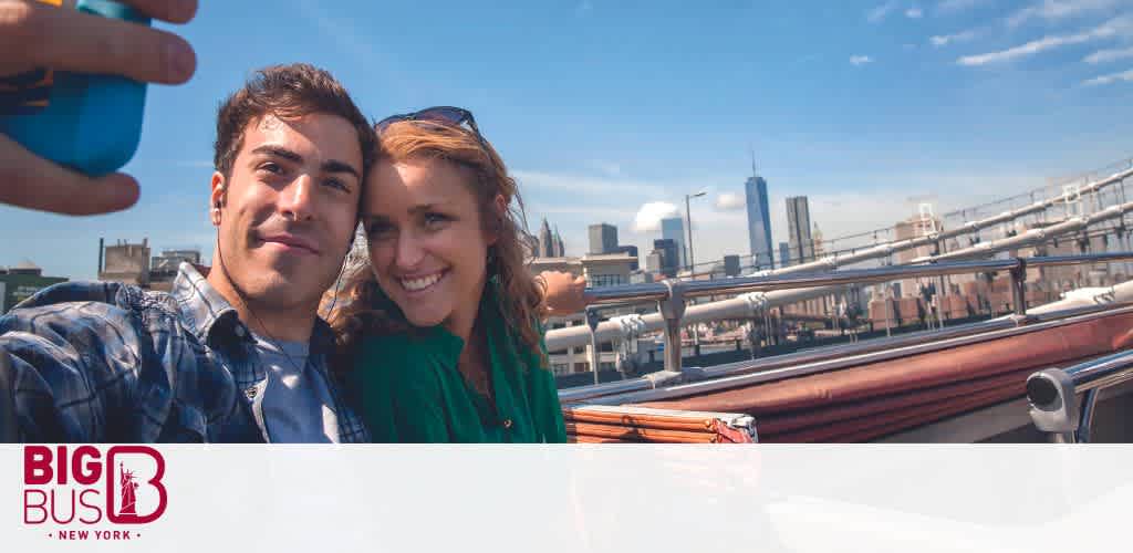 A smiling pair takes a selfie on a Big Bus New York tour, showcasing a sunny skyline with iconic structures in the background, invoking the joy of urban exploration.