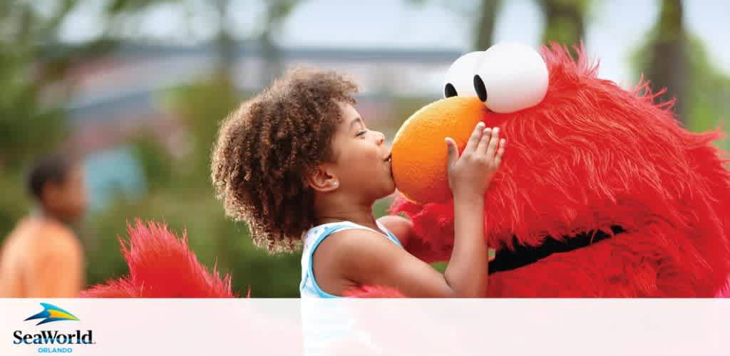 Child kisses a red furry character at SeaWorld Orlando.