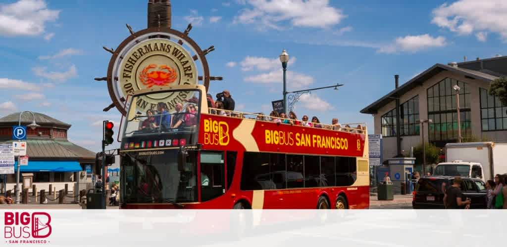 Open-top red tour bus at Fisherman's Wharf under blue sky.