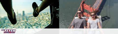 This image is a split-view showing two different scenes side by side, both related to 'THE FLYER' attraction. On the left, an aerial view of a cityscape from a high altitude, with skyscrapers reaching up towards the viewer. A person's legs, clad in black pants and shoes, dangle into the frame from the top, suggesting they are suspended above the city, perhaps on a ride or platform overlooking the urban expanse. The right-hand side of the image features a young man and woman, both wearing glasses, strapped into red seats of what appears to be a thrill ride. They are both clad in casual, light-colored clothing and look outward with expressions of excitement and slight apprehension. Their hair and clothes are ruffled by the wind, indicating motion, likely the thrill of the ride in action. The overall impression is one of exhilarating experiences, with both views offering a sense of adventure and height.

Find your next thrilling adventure at discounted rates with GreatWorkPerks.com, where savings soar as high as your spirits with our lowest prices on tickets.