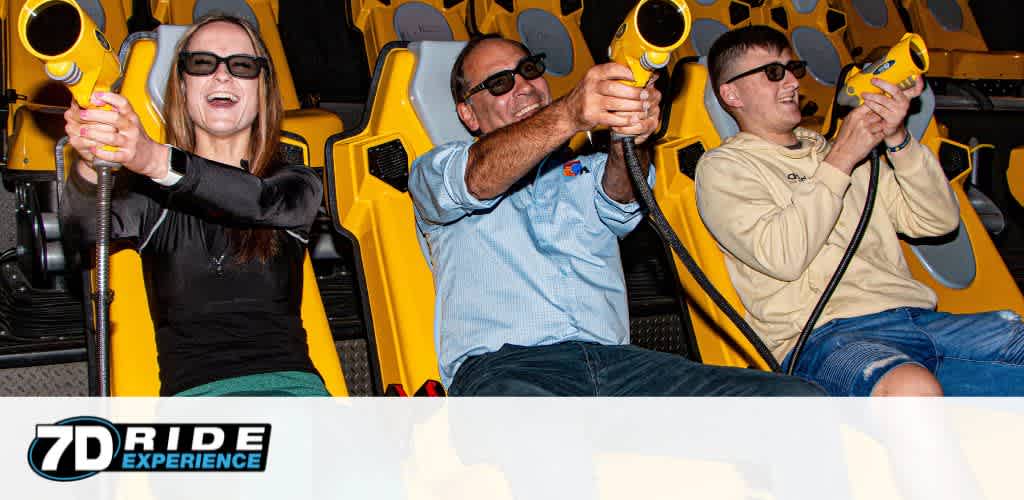 This image features three individuals engaged in an exciting 7D ride experience. The first person, on the left, appears to be a woman with long hair, wearing a black long-sleeve top and 3D glasses, smiling while holding onto a yellow and black interactive ride gun. In the center, there is a man wearing a short-sleeve button-up shirt and sunglasses, also holding an interactive gun with a delighted expression. To the right, another individual, donning a casual light-colored shirt and sunglasses, is eagerly using a similar device. All three are seated in a motion-simulated ride vehicle with vibrant yellow accents and are secured by over-the-shoulder restraints. They seem to be having a thrilling experience, indicated by their joyous expressions and the dynamic environment of the ride featuring immersive screens and special effects.

At GreatWorkPerks.com, we're passionate about bringing you the excitement without the high price tag, offering unbeatable discounts and the lowest prices on tickets for a variety of entertainment options.