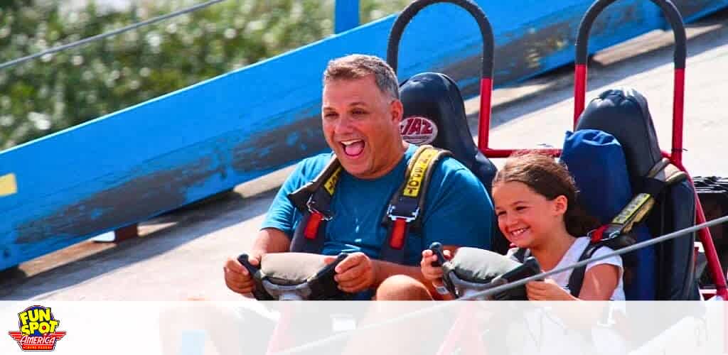 Adult and child enjoy a ride at Fun Spot America, expressing joy.