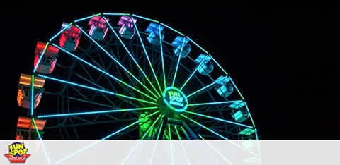 Illuminated Ferris wheel at night with colorful lights.