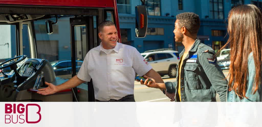 Image Description: A cheerful bus driver wearing a white shirt with a 'BIG BUS' logo is standing by the open door of a red sightseeing bus, greeting passengers. The driver is extending a welcoming gesture towards a young man who appears to be in conversation with him. The young man, facing the driver, is wearing a dark green jacket adorned with a small flag patch on the arm. To his right stands a young woman with her back partly towards the camera, wearing a blue denim jacket. They are on a city street with cars parked in the background under a clear blue sky.

Experience your adventure without spending a fortune! Use GreatWorkPerks.com to find amazing discounts and the lowest prices on tickets for top attractions and tours.