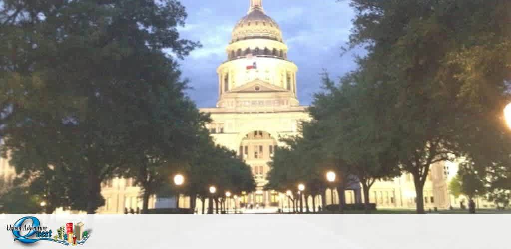 Image shows a twilight view of the Texas State Capitol building with its distinguished dome and classical architecture. The pathway leading to the Capitol is lined with street lamps casting a warm glow. Trees flank either side of the walkway. The sky is fading from blue to dusk. At the bottom, there's a logo for Urban Adventure Quest.