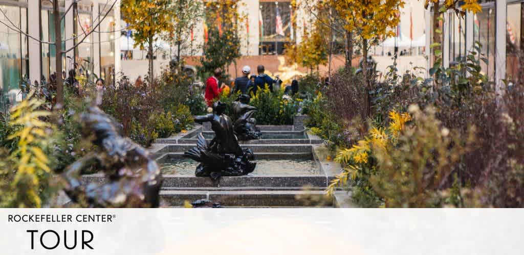 Image shows a tranquil garden pathway at Rockefeller Center with autumn-hued foliage. Bronze sculptures and visitors can be seen. The text 'Rockefeller Center Tour' indicates a tourist experience.