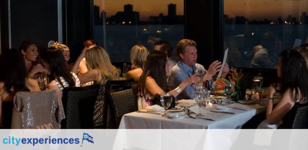 A group of people enjoys a dining experience at a restaurant with dim lighting. They are seated at a table set with glassware and dinnerware, engaged in conversation and looking at menus. A city skyline is visible through the window in the background. The logo of City Experiences is featured in the lower-right corner.