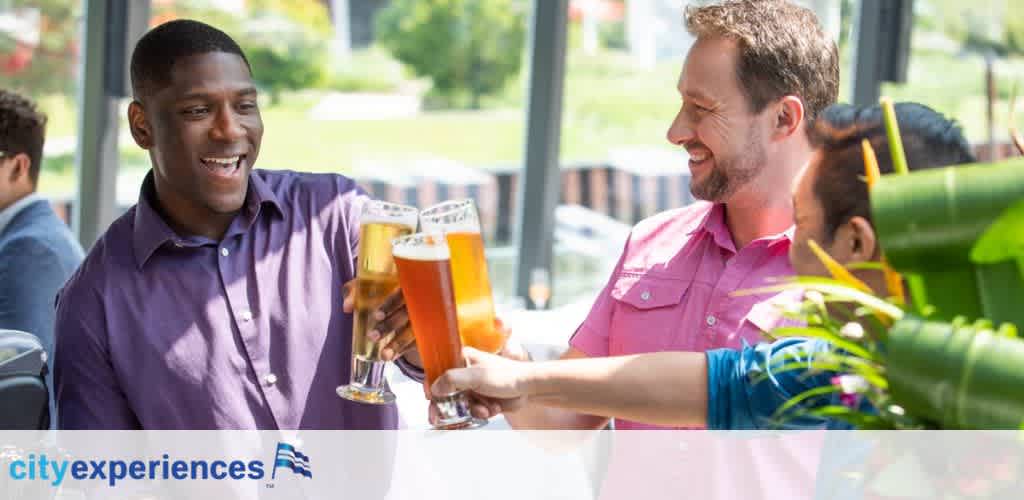 Two people are cheerfully toasting with glasses of beer at a brightly lit venue. One person is wearing a purple shirt and smiling, while the other, in a pink shirt, clinks his glass in response. The City Experiences logo is visible at the bottom, and the setting suggests a casual social gathering with others around them.