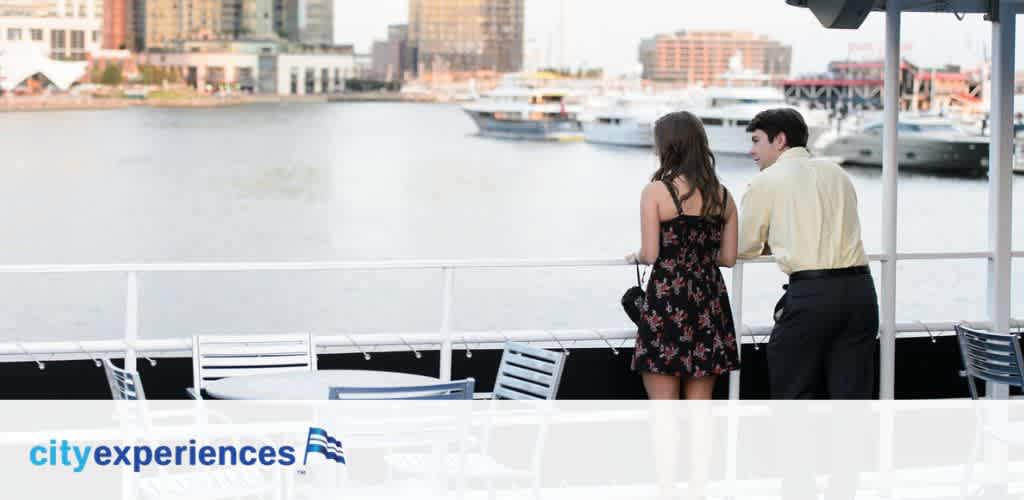 Two individuals are standing together at the railing of a boat, overlooking a calm body of water with a cityscape in the background. Below is the logo for City Experiences, consisting of text and a stylized flag.