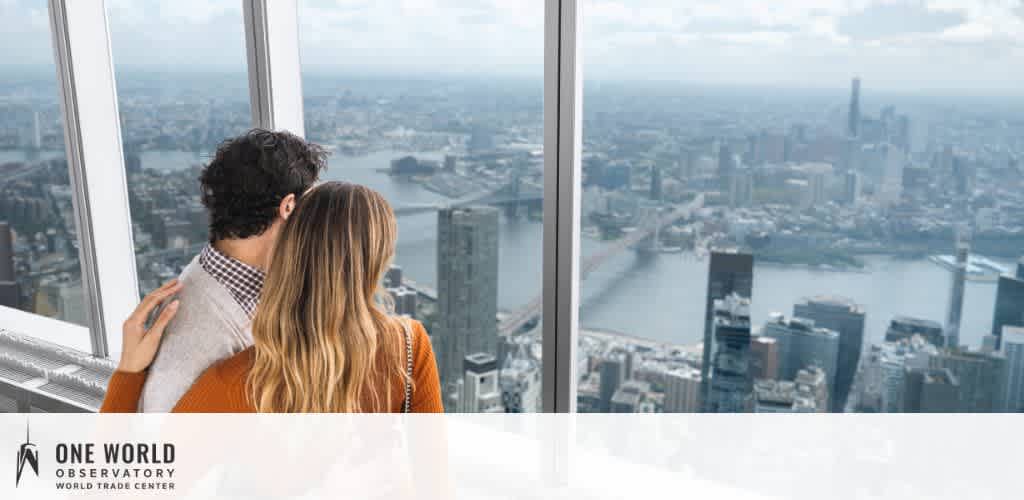 Two people looking out at a cityscape from inside a high-rise building.