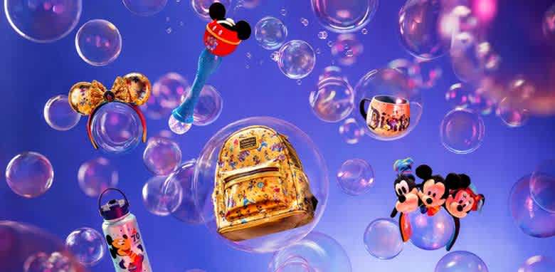 Colorful Disney-themed merchandise floats inside translucent bubbles against a vibrant purple background. Featured items include a golden backpack, character-themed hair accessories, a tumbler, a water bottle, and a decorative mug. The playful arrangement creates a whimsical and fun atmosphere, appealing to fans and collectors of all ages.