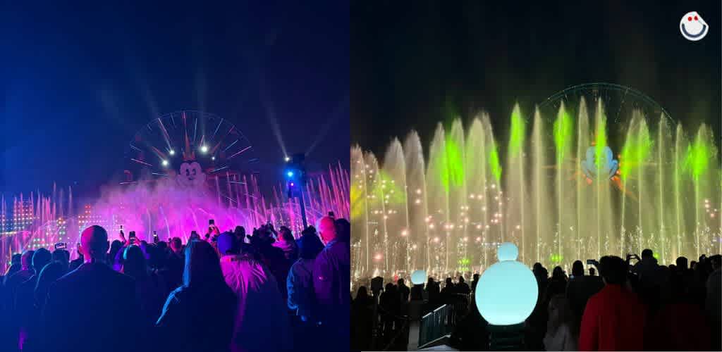 A lively night scene at a theme park features a large illuminated ferris wheel as colorful water fountains dance in front. The crowd is gathered in the foreground, enjoying the vibrant light and water display against the night sky, creating a festive and enchanting atmosphere.