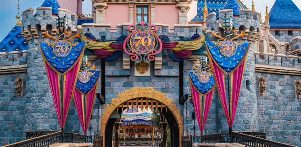 A beautiful castle adorned with ornate turrets and vibrant banners celebrating a milestone. The stone facade features intricate architectural details. Colorful flags with decorative designs hang on either side of the entrance. The gate opens into a magical courtyard, hinting at a carousel in the background. The scene embodies a sense of enchantment and festivity, inviting guests into a world of wonder.