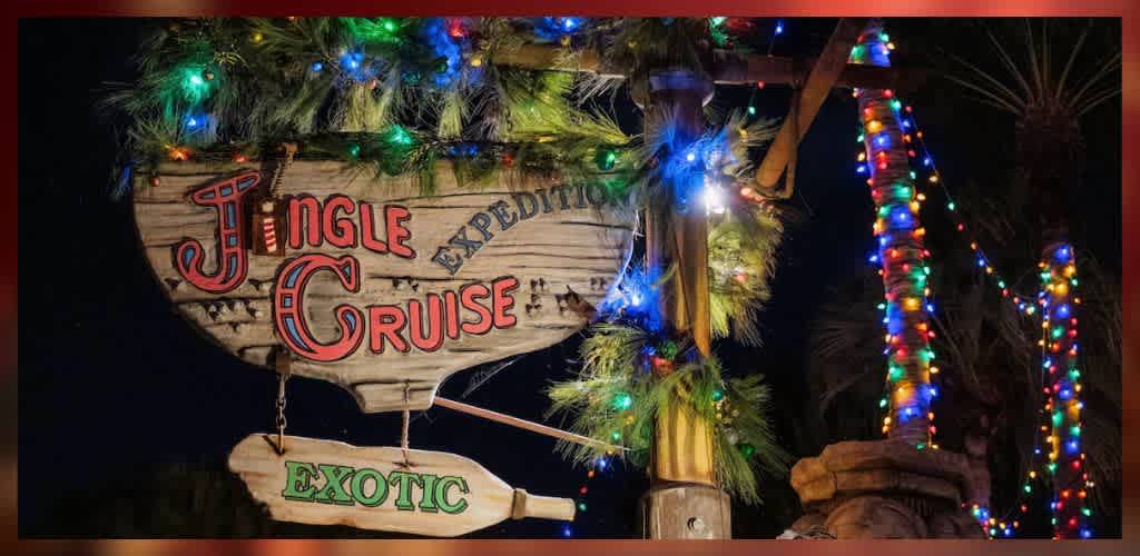 Wooden Jingle Cruise sign adorned with colorful holiday lights and greenery, creating a festive atmosphere against a dark night backdrop. The words Jingle Cruise are highlighted in red with Expedition and Exotic in smaller letters, adding to the adventurous theme. Strings of multicolored lights wrap around nearby structures, contributing to the cheerful holiday setting.
