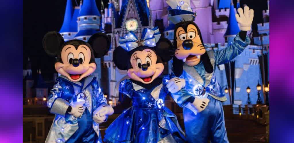 Three iconic cartoon characters dressed in sparkling blue outfits stand in front of a brightly lit castle at night. The characters wear matching attire featuring glowing white lights and cheerful expressions. The scene exudes joy and excitement, capturing the magic of a festive celebration in a theme park setting.