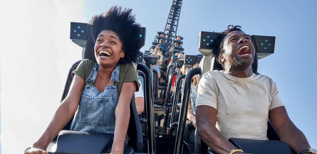 Two people are laughing joyfully while riding a roller coaster, capturing a moment of thrill and excitement.