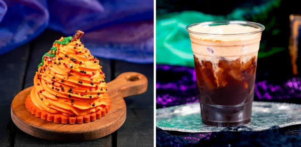 A close-up of a Halloween-themed cupcake with orange frosting, sprinkles, and a small decoration, placed on a wooden board. To the right is a glass of iced cola.