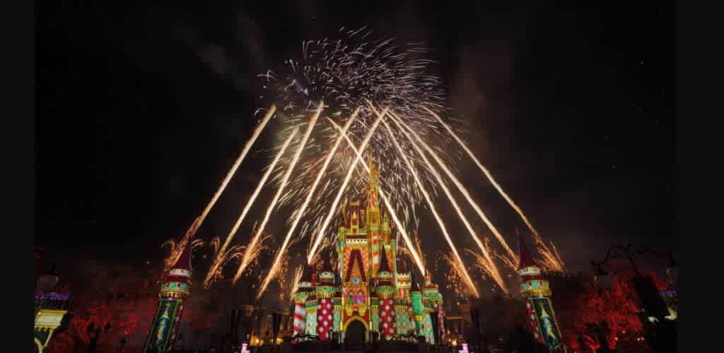 Fireworks explode over a colorful castle at night during a celebration at Disneyland.