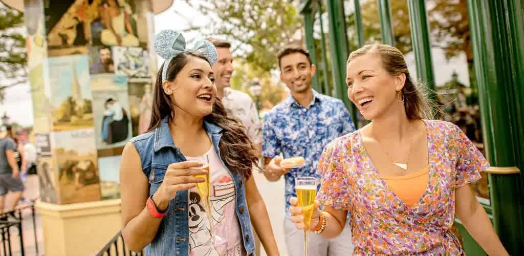 Group of people smiling and holding drinks outdoors at a festive event in a lively park setting