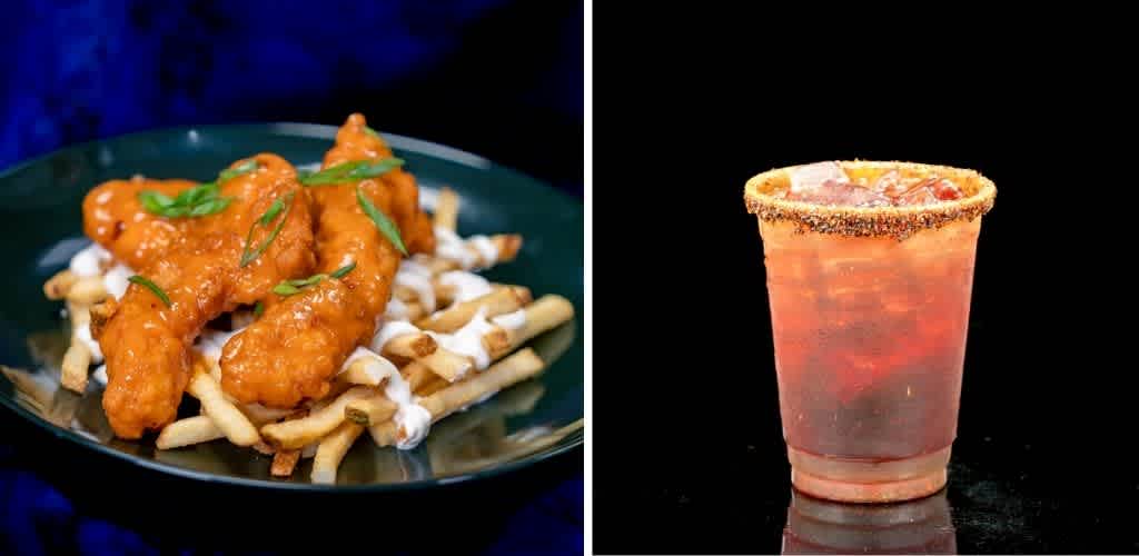 Plate of crispy chicken wings with sauce and green garnish on fries with white queso and green onion, next to a glass of pink soda with salted rim on black background.