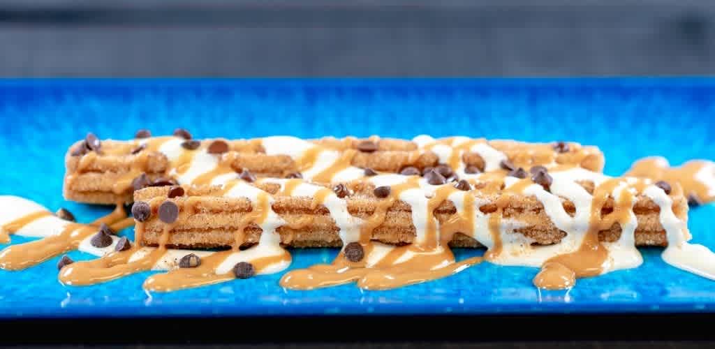 Close-up of cinnamon toast cereal with milk, caramel, and chocolate drizzle on a blue plate.