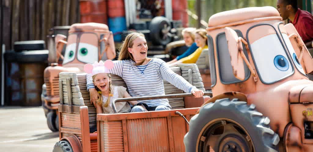 Children enjoying a fun ride on a colorful cartoon-style tractor amusement park attraction.
