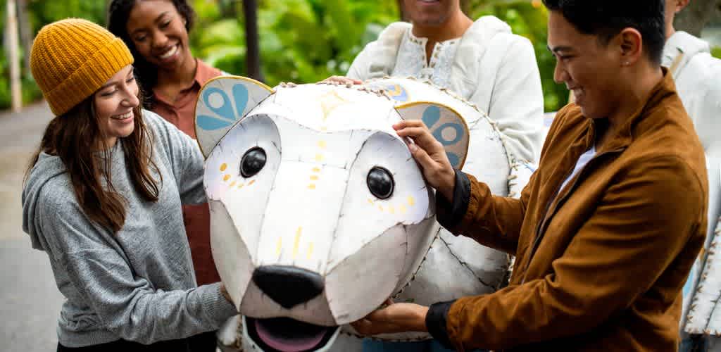Group of people smiling and creating a large animal-shaped sculpture outdoors