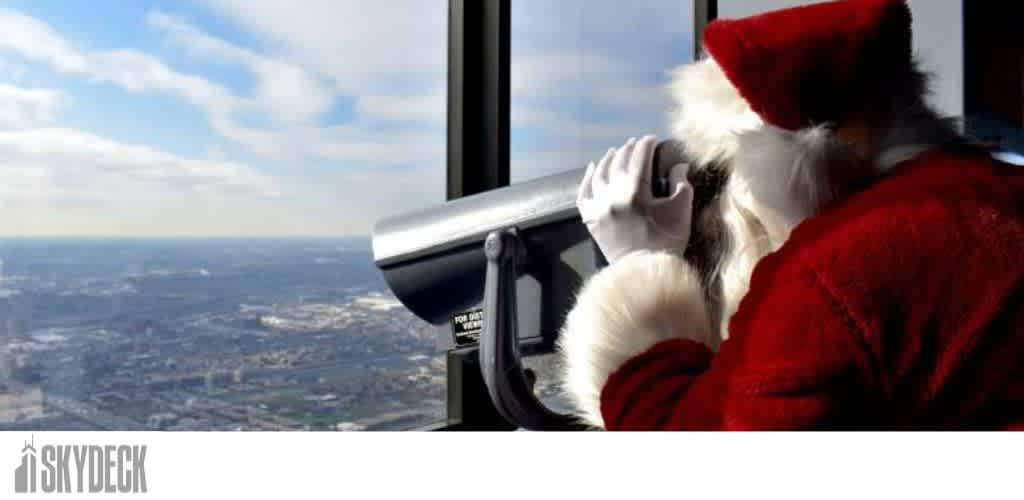 Santa Claus looking through a telescope towards a cityscape.